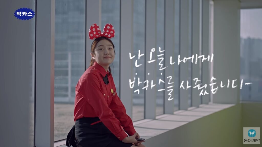 박카스 CF의 한 장면, 20대 여성이 뿌듯한 표정으로 미소짓고 있고, '난 오늘 나에게 박카스를 사줬습니다.'라는 문구가 있다. 동아제약의 박카스